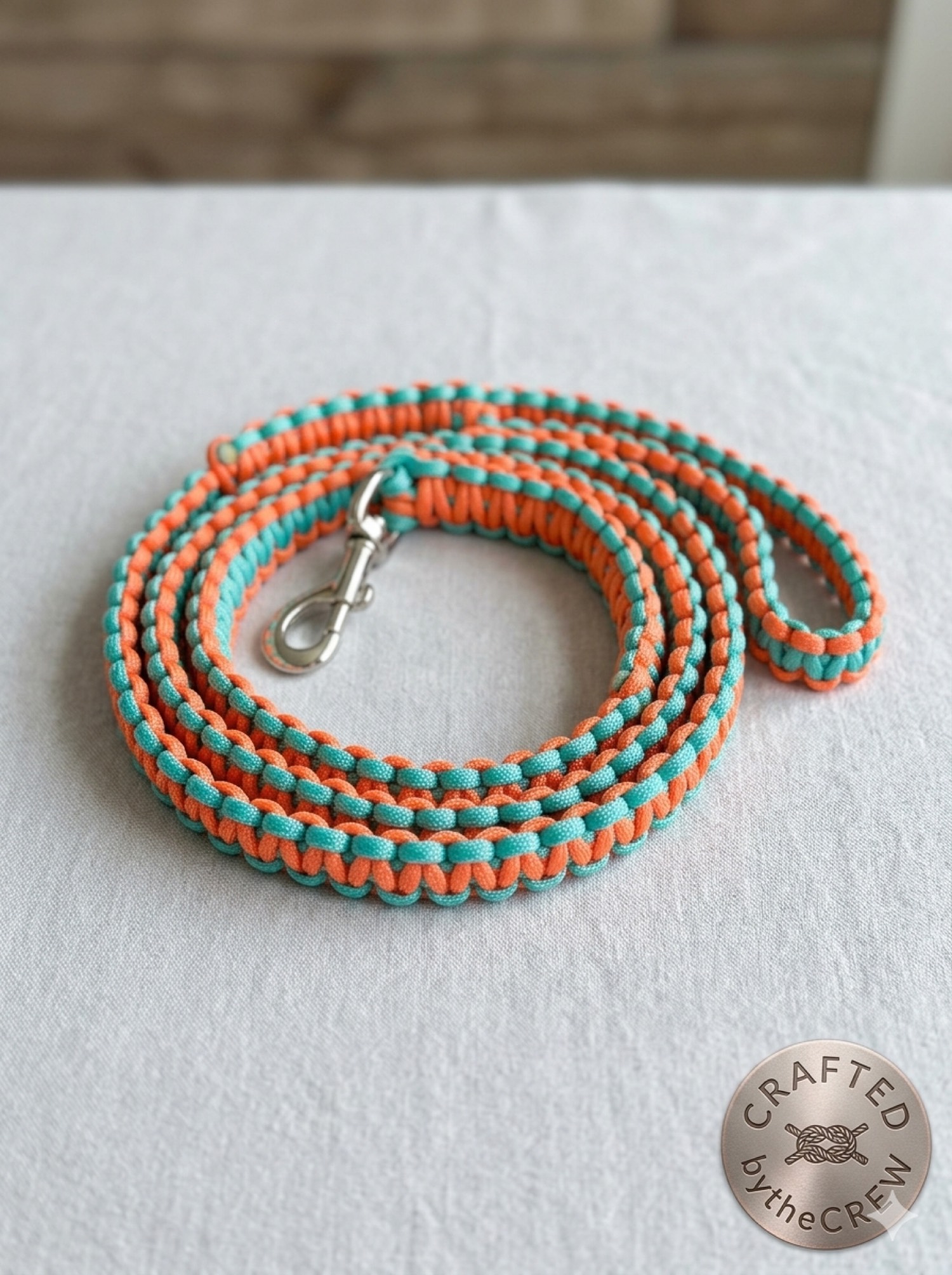 Coral and aqua paracord leash coiled on white cloth